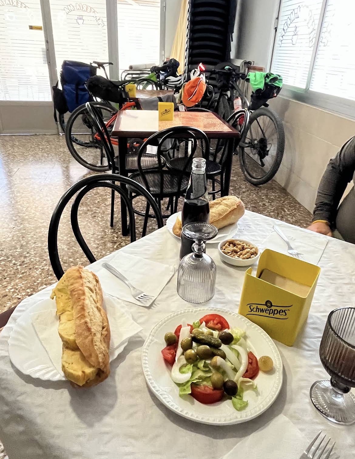 Mesa del salón con bocadillo, ensalada y bicicletas al fondo