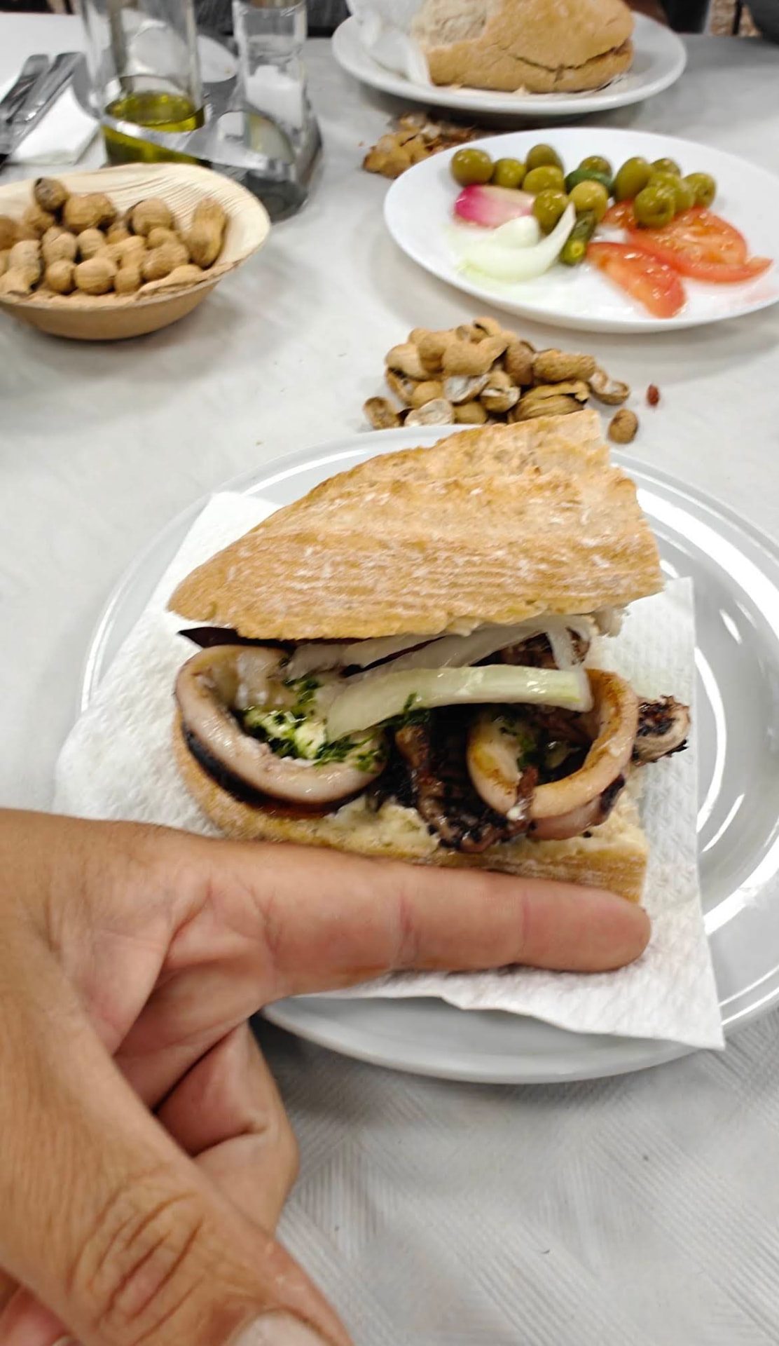 Bocadillo de calamares con cebolla y perejil sobre plato blanco